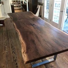 a large wooden table sitting on top of a hard wood floor next to a sliding glass door