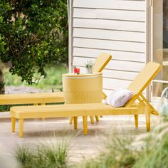 a yellow lounge chair sitting on top of a patio next to a table and trash can