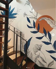 the stairs are painted with blue leaves and orange circles on them, along with a wall mural