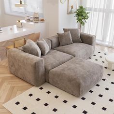 a large sectional couch sitting on top of a wooden floor next to a white table