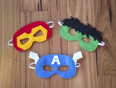 three masks with the letter a on them sitting on a wooden floor next to each other