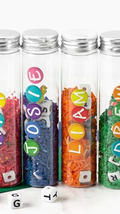 three glass jars filled with letters and numbers on top of each other in different colors