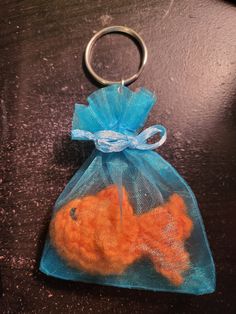 an orange fish in a blue organ bag on a wooden table with a metal keychain