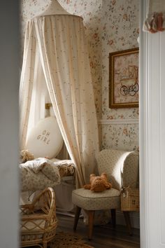 a teddy bear sitting on a chair in front of a canopy bed with curtains over it