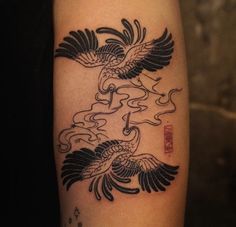 a black and white tattoo on the arm of a woman with two birds flying over water