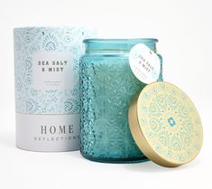 a blue jar with a lid next to a candle and box on a white background