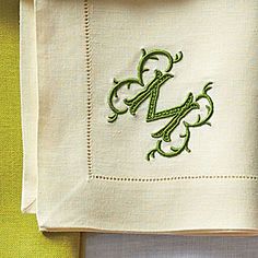 the monogrammed letter m is on top of a white napkin with green embroidery