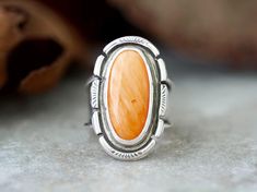 Bold Orange Spiny Oyster Sterling Silver Statement Ring for women. The setting is an oval cabochon 20mm x 10mm that is in a Bezel setting. The 925 Sterling Silver has been fused, stamped and lightly oxidized. This ring has a tapered wide band 1/2" then narrows to 1/8" and cannot be resized. Size 6 The sleek, embellished setting is complemented by a unique tapered chunky silver band, ensuring durability and timeless style. Whether you're shopping for yourself or are searching for the one of a kin Orange Ring, Vero Beach Fl, Handmade Gifts For Her, Statement Ring Silver, Spiny Oyster, Handmade Boho, Wide Bands, Oval Cabochon, Boho Rings