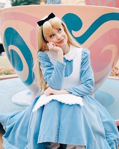 a woman in a blue dress is sitting on a bench