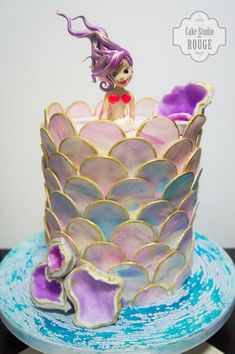 there is a cake that looks like a mermaid sitting on top of a large shell