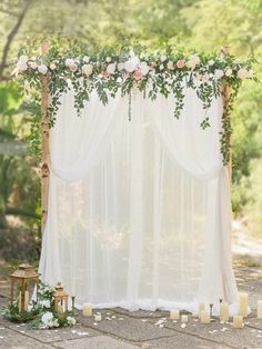 a white wedding arch with flowers and candles