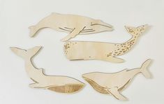 four wooden cutouts of whales on a white background