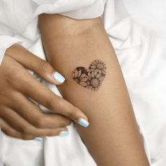 a woman's arm with flowers on it and a small heart tattoo in the middle