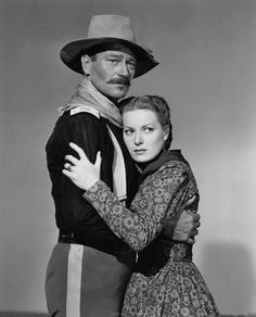 an old black and white photo of a man in a cowboy hat hugging a woman