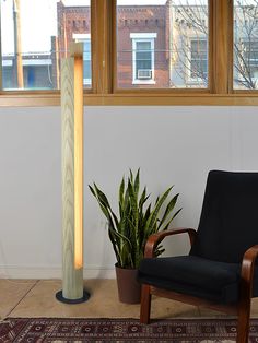 a chair sitting in front of a window next to a potted plant on a rug