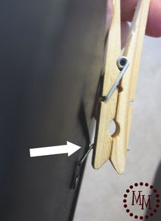 a pair of scissors being held to the side of a piece of wood with an arrow pointing at it