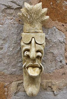 a stone mask with a mohawk on it's head next to a rock wall