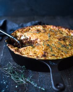 a casserole with meat and cheese in a black pan on a wooden table