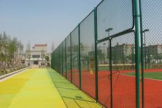 an image of a tennis court fence with red clay and green grass in the background