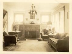 an old black and white photo of a living room with couches, chairs and a fireplace