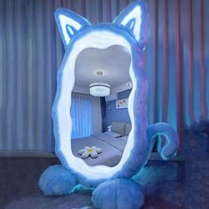 a blue cat shaped mirror sitting on top of a wooden floor next to a bed