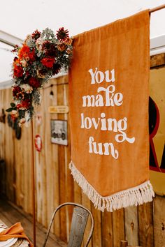 an orange banner with the words you make loving fun hanging on a wooden wall next to a table