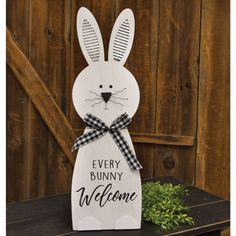 a wooden sign that says, every bunny is welcome with a black and white checkered bow