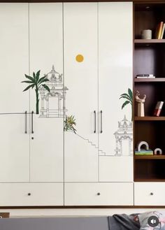 a white cupboard with drawings on the doors and shelves next to bookshelves in a living room