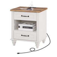 a white night stand with two drawers and a book on the bottom shelf next to it