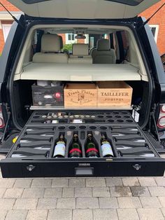 the back end of a van with bottles in it and two boxes full of wine