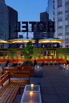 an outdoor dining area with tables, benches and umbrellas lit up in the evening