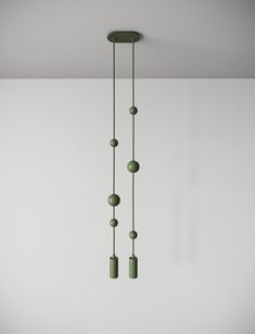 three green lights hanging from the ceiling in a room with white walls and flooring