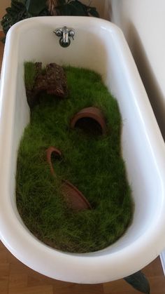 a bathtub that has grass in the shape of an animal's head inside