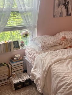 a bed with white sheets and pillows in a bedroom next to a window filled with books