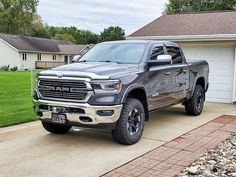 a silver ram truck parked in front of a house with a white garage behind it