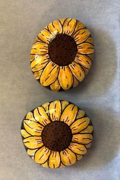 two yellow sunflowers sitting on top of a gray countertop next to each other