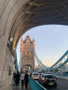 people are walking on the bridge near cars