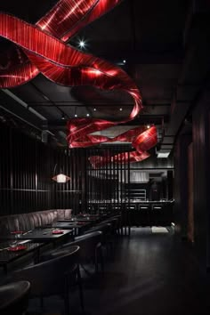 a dimly lit restaurant with red lights hanging from the ceiling and black leather booths on either side