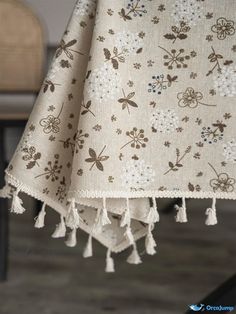 a table cloth with flowers on it and tassels hanging from the end of it