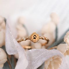 a gold ring with a dog's paw on it sitting next to some flowers