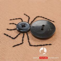 a black spider button sitting on top of a piece of fabric next to a pair of scissors