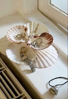 two seashells are sitting on a window sill with key chains attached to them