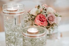 two vases with flowers and candles on a table