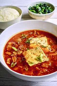 a bowl of soup with tofu, rice and broccoli on the side