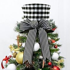 a decorated christmas tree with black and white ribbon, ornaments and bow on the top