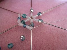 a close up view of beads and needles on a pink surface