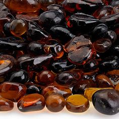 many different colored glass beads on a white surface with one being black and the other is brown