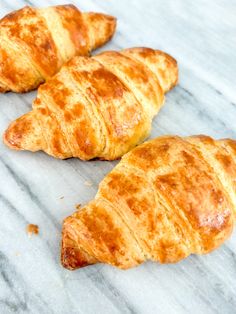 three croissants sitting on top of a white marble counter next to each other