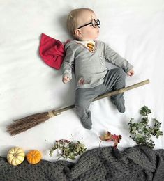 a baby laying on top of a bed with a broom