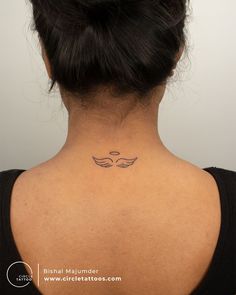 the back of a woman's neck with an angel wing tattoo on her left side